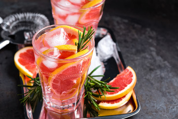 Grapefruit and fresh rosemary gin cocktail with juice, cold summer citrus refreshing drink or beverage with ice