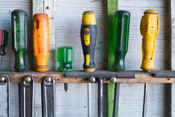 Old hand tools hanging on wall in workshop or auto service garage, many tool shelf against a wall, car mechanic concept.