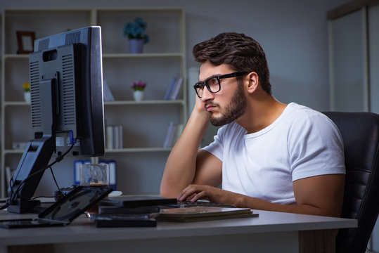 Young Man Staying Late In Office To Do Overtime Work