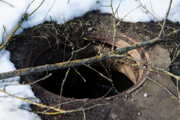 Dangerous manhole without a cover laid wooden planks closeup