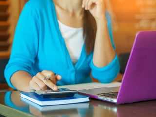 Closeup business woman hand using a calculator with credit card for online payment in cafe office. Business finance concept.