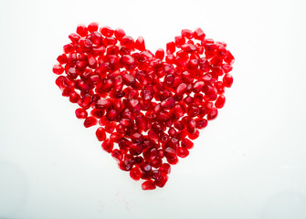 Fototapeta na wymiar Red juicy garnet in the form of a heart isolated on white background