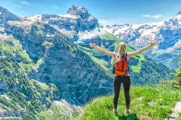 girl traveler, arms outstretched, against the backdrop of mountain peaks, the Engelberg resort, Switzerland