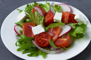 Fresh salad from salmon and vegetables on a white plate.