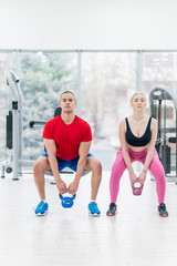 Fototapeta premium sport, fitness, weightlifting and training concept - group of people with kettlebells exercising in gym