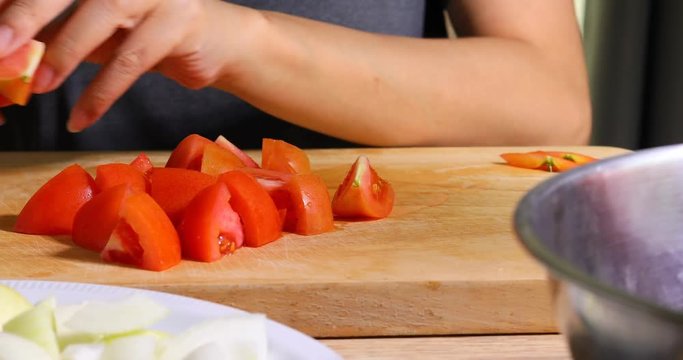 chef cooking food sliced tomato with knife on wooden chopping boar