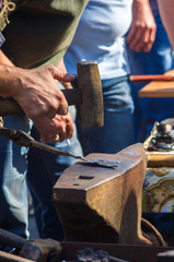 blacksmith performs the forging of hot glowing metal on the anvil