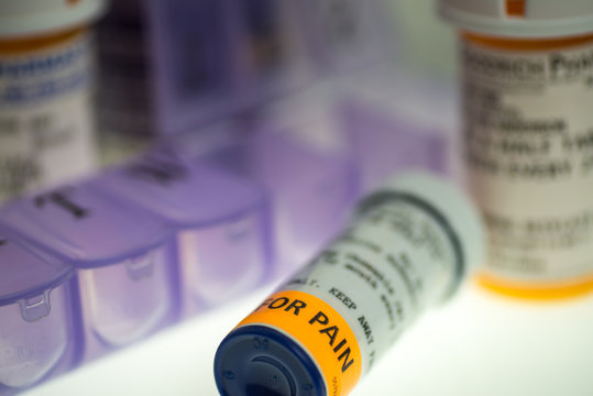 horizontal image of prescription pain medication bottles and weekly pill organizer. shallow depth of field with room for copy. 