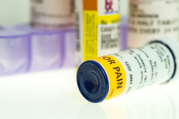 horizontal image of prescription pain medication bottles and weekly pill organizer. shallow depth of field with room for copy. 