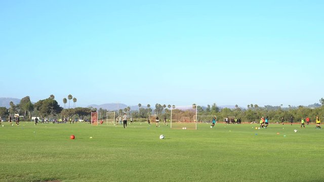 4K Soccer Practice. Children playing soccer on a field in California.