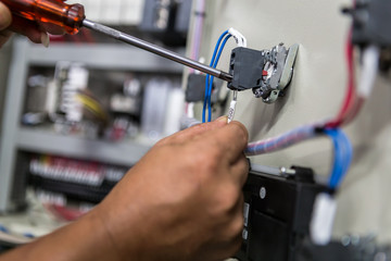 Electricians hands repair switches in electric control
