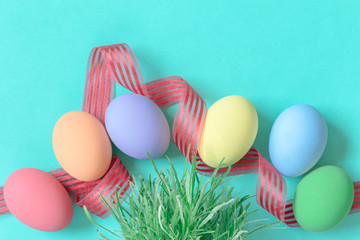 pastel easter eggs on green background in top view