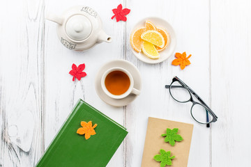 Book, cup of tea, teapot, candy and glasses, flat lay. Cozy background, reading concept. Copy space