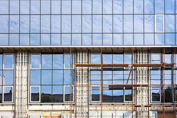 wall of glass office building facade under construction with scaffolding