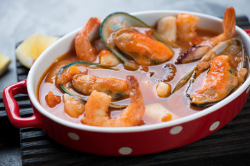 Close-up of buyabes or french fish soup with addition of green mussels, tiger shrimps and calamari, selective focus