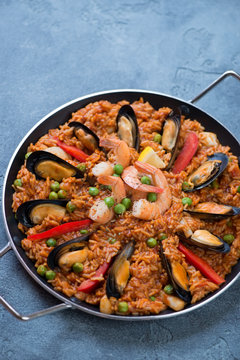Frying pan with spanish traditional seafood paella over blue stone background, studio shot