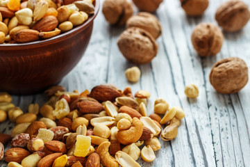 Mix nuts in earthenware on a wooden background.