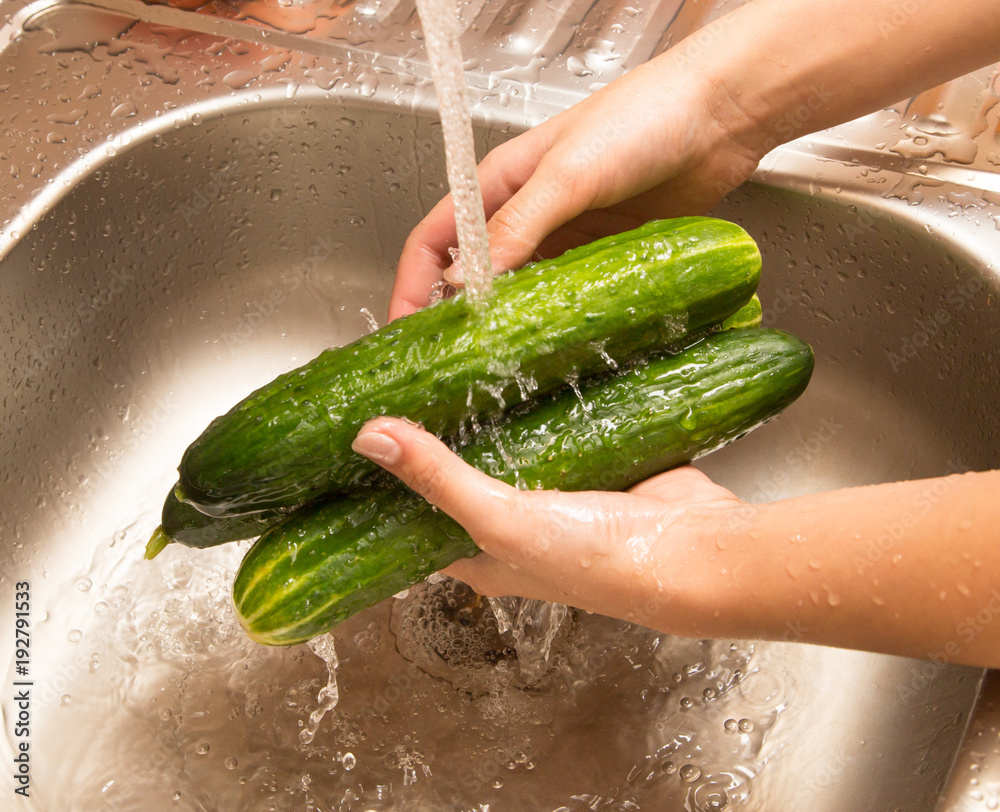 Sticker Washing fresh cucumbers in the water under the tap