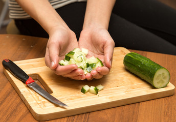 Slicing cucumber with a knife on the board