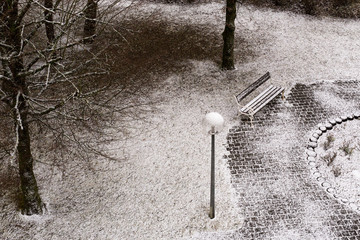 Park bench and slightly snow-covered ground from a bird's eye view