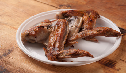 Fried chicken wings in a white plastic plate on the wooden table,