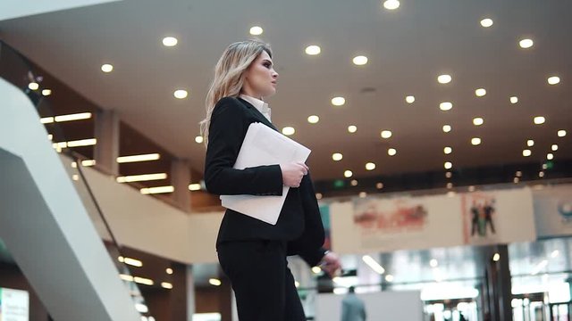 girl manager walks down the lobby of the office building and holds the papers in her hands. business woman in the office