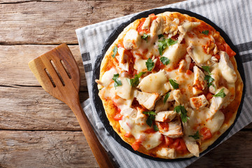Buffalo pizza with chicken breast, tomato concasse and cheese close-up. horizontal top view