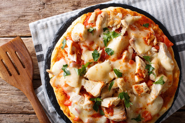 Spicy pizza with chicken, tomatoes, buffalo sauce and cheese close-up. horizontal top view