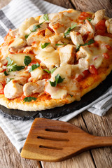 freshly cooked pizza with chicken, tomatoes, buffalo sauce and cheese close-up. vertical