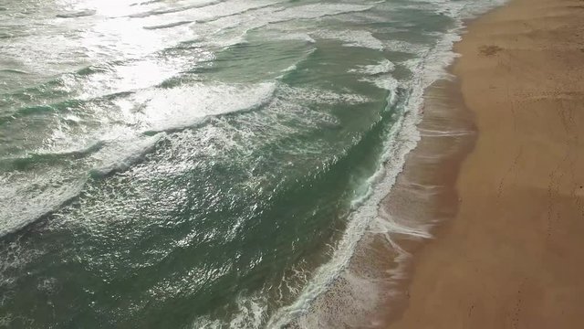 Slow aerial desend towards Welcome to Australia large words written on ocean beach at sunset