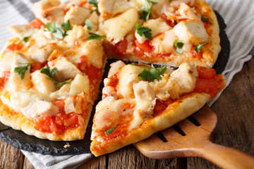 Hot sliced buffalo pizza with chicken, tomatoes and cheese macro on the table. horizontal