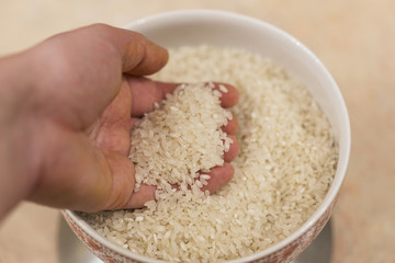 A hand takes a handful of rice. Close-up
