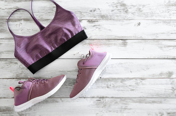 Womens sport bra and sneakers on wooden background with copy space. Active running (walking) footwear
