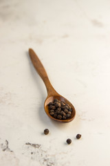 Black pepper peas on a wooden spoon, light background