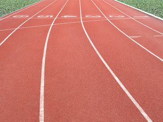 running track with lane numbers and green grass in outdoor athletic stadium