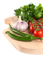 tomatoes, parsley, garlic and green peppers on the wooden cutting board, white background