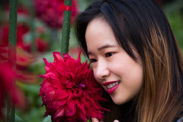 Beautiful woman posing next to red flowers in a Japanese garden