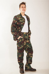 A young guy wearing a camouflage uniform. Military man on white background.