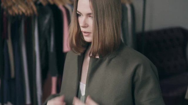 Young woman trying on coat in clothing store