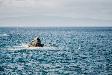 Fototapeta premium Single rock in the ocean and the island on the background. Los Gigantes Tenerife