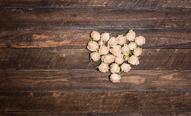 Vintage heart from dried roses flowers on wooden table with copy space. Retro styled valentin day...