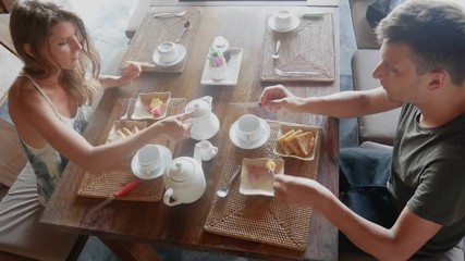 Young couple talking eating and drinking coffee sitting on terrace