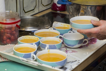 A tray is prepared with bowls filled with yellow soup