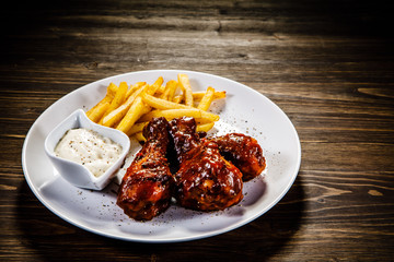 Barbecued drumstick with french fries on wooden table