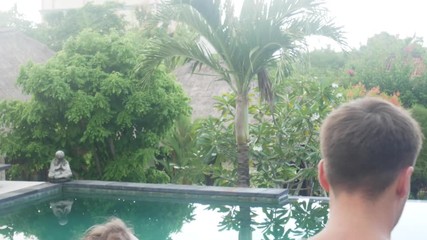 Couple holding hands of each other and walking in the tropical park. Young Man and woman going along exotic the territory of the resort. Summer vacation trip concept.