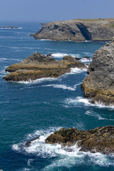 The sea is blue, the waves break on the rocks and the tormented cliffs on the wild coast of Belle-Ile, Brittany, France