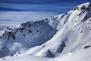 Two back country skiers looking forward at the steep mountain