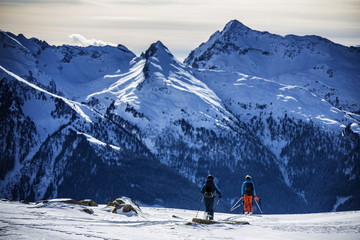Fototapeta na wymiar Two back country skiers looking forward at the steep mountain