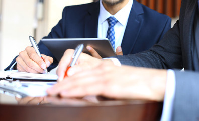 Two young businessmen analyzing financial document at meeting.