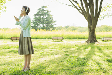 Naklejka premium 公園で音楽を聴く女性